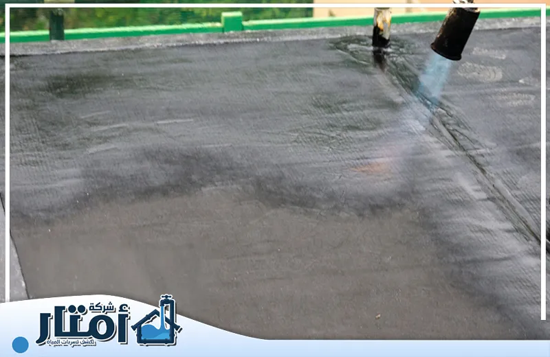 شركة عزل اسطح بخميس مشيط 0502032828 أمتار البناء رجل يعمل على تسخين مادة عزل اسطح بخميس مشيط باستخدام معدات خاصة.